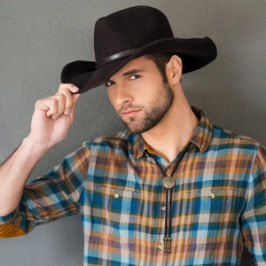 Western cowboy Bolo Tie with gold bull head pendant, brown hat, and plaid shirt