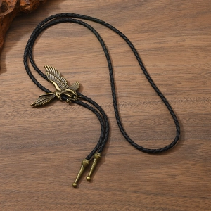 Cravate bolo aigle vintage avec pendentif en bronze et cordon tressé noir sur fond bois