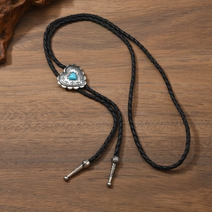 Gros plan sur une cravate bolo cœur turquoise avec métal argenté sur bois de noyer foncé