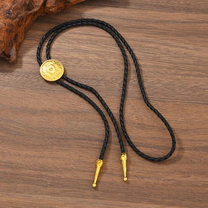 Detail of vintage bolo tie with gold floral carved slider and black leather cord