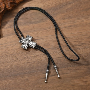 Détail du bolo tie croix argentée vintage avec cordon tressé sur surface en bois