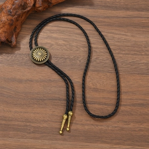 Vintage western cowboy bolo tie with gold sunburst engraved slider on wood background