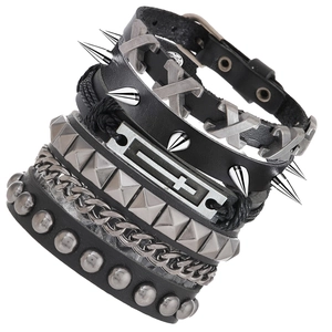 Détail de bracelets punk multicouches en cuir avec pointes argentées, rivets et breloque croix