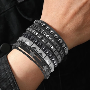 Detail of layered punk bracelet set featuring black leather straps and metal rivets