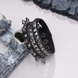 Punk leather bracelet set with metal studs, chains, and rivets on a stone background