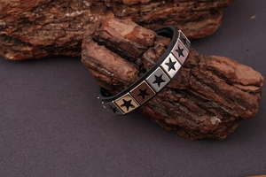 Detail of punk leather wristbands with star-stamped metal studs on rustic bark background