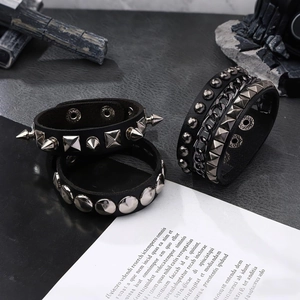 3-teiliges Punk-Lederarmband-Set mit Metallnieten und Ketten auf dunkler Steinoberfläche