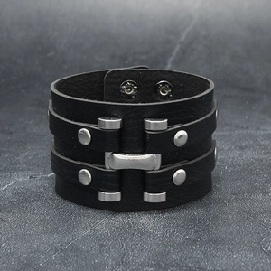 Close-up of wide black punk leather bracelet with silver H-shaped metal and rivets