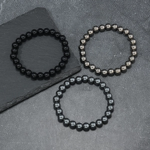 Tiger eye and hematite beaded bracelet set for couples on dark stone background