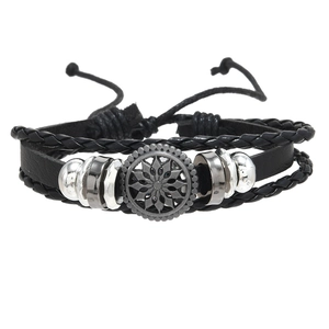 Macro detail of multi-layer leather braid bracelet with sun pattern metal disk
