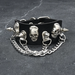Detail of punk black PU leather bracelet featuring silver metal skulls and sharp studs