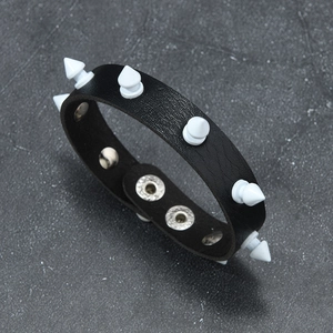 Detail of black punk leather bracelet featuring white conical studs and metal snaps