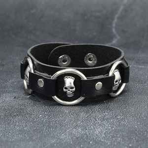 Close-up of black leather punk bracelet with silver skull charms and snap buttons