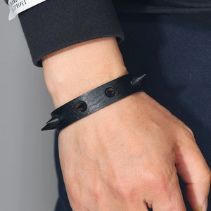 Punk style black leather bracelet with metal spikes worn on wrist close-up view
