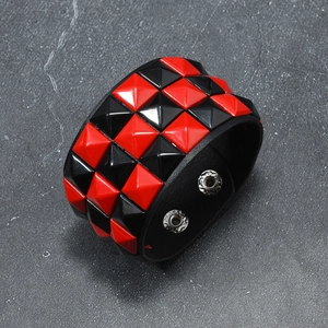 Detail of red and black square studs on punk leather bracelet with silver snap buttons