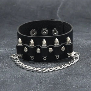 Détail d'un bracelet en cuir noir punk avec rivets argentés et chaîne métallique