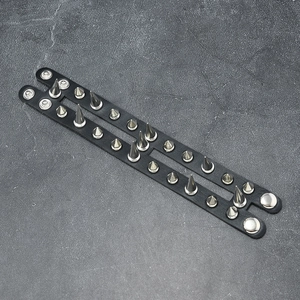 Dettaglio del bracciale punk in pelle con doppia fila di borchie argentate e bottoni a pressione