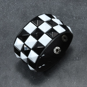 Detail of wide black leather punk bracelet with black and white pyramid studs and metal snaps