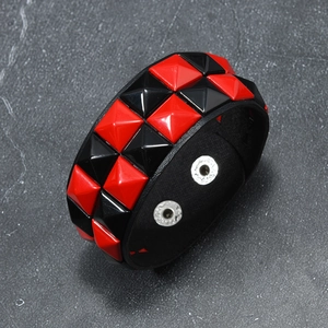 Detail of punk leather bracelet featuring red and black square pyramid studs with silver snaps