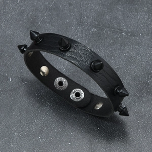 Detail of black punk leather bracelet with conical spikes and metal snap fastener