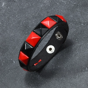 Close-up of punk leather bracelet with red and black square pyramid studs and snap buttons