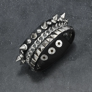 Punk rock leather bracelet with silver metal spikes and chain on stone background