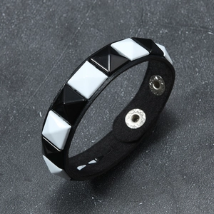 Detail of punk rivet bracelet featuring black and white pyramid studs and snap buttons