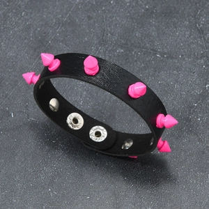 Detail of black leather punk bracelet with neon pink spikes and metal snap fasteners