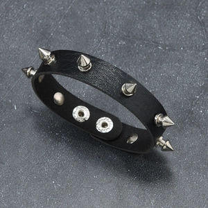Macro detail of black punk leather bracelet featuring silver metal spikes and snap buttons