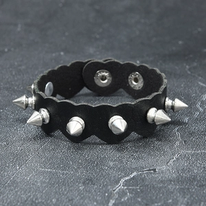 Detail of punk leather bracelet featuring silver cone spikes and scalloped heart edges