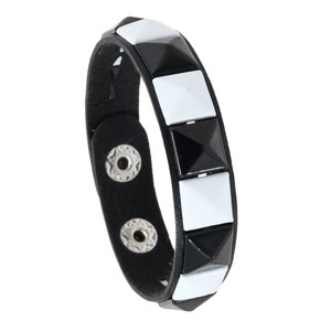Detail view of punk rivet bracelet with black and white pyramid studs and silver buttons