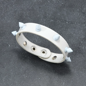 Detail view of white leather punk bracelet featuring blue spikes and metal snap buttons
