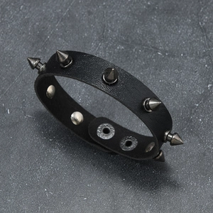 Detail of punk leather bracelet featuring black litchi texture and metal conical studs