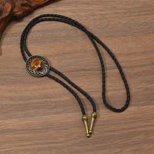 Vintage western bolo tie with tiger eye stone and braided leather rope on wood background