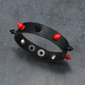 Macro view of punk leather bracelet with alternating red and black spikes and silver snaps