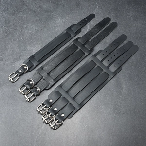 Detail of adjustable metal pin buckles and grainy black leather texture on punk bracelets