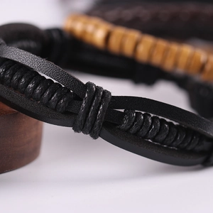 Macro shot of hand-woven black leather bracelet and wooden beads in a layered jewelry set