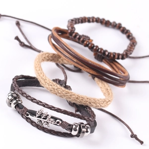 Macro detail of alloy maple leaf charm on multilayer leather and hemp rope bracelet
