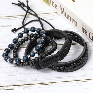 4-piece set of multilayer beaded and black leather braided bracelets on white wood