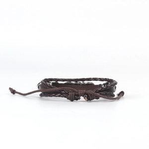 Detail view of multi-layer brown braided bracelet with metal charms and sliding knot