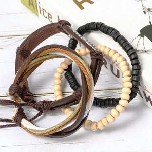 Multilayer men's leather bracelet set with wooden beads and woven rope on white wood background