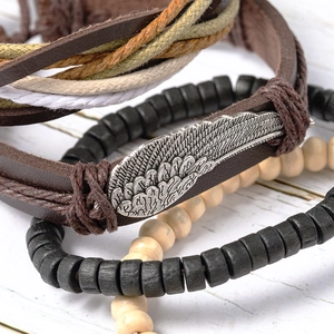 Ethnic layered beaded bracelet featuring a vintage silver wing charm and woven leather