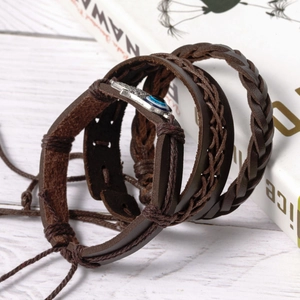 Multilayer leather bracelet with silver Evil Eye charm on white wooden tabletop