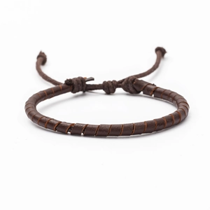 Detail of dark brown braided leather bracelet with adjustable drawstring knot and woven texture