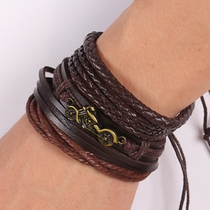 Close-up of retro punk leather bracelet featuring layered braids and a bronze motorcycle charm