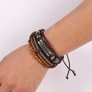 Detail of multi-layer leather bracelet with hope metal plate and wooden beads