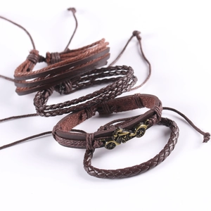 Detail of vintage punk leather bracelets with bronze motorcycle charm and woven bands