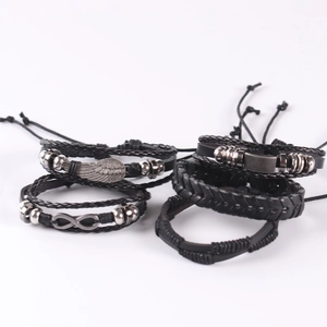 Detail of multi-layer black braided leather bracelets with wing and infinity charms