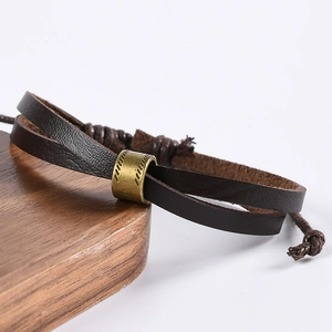 Lot de bracelets en cuir marron tressé avec tubes métalliques bronzes sur bois