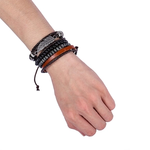 Detail view of multi-layer ethnic bracelet with leather cords, beads and feather charm